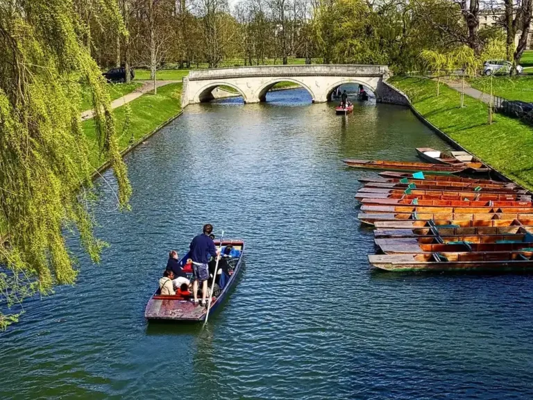 A punt gliding past moored punts on the River Cam in Cambridge