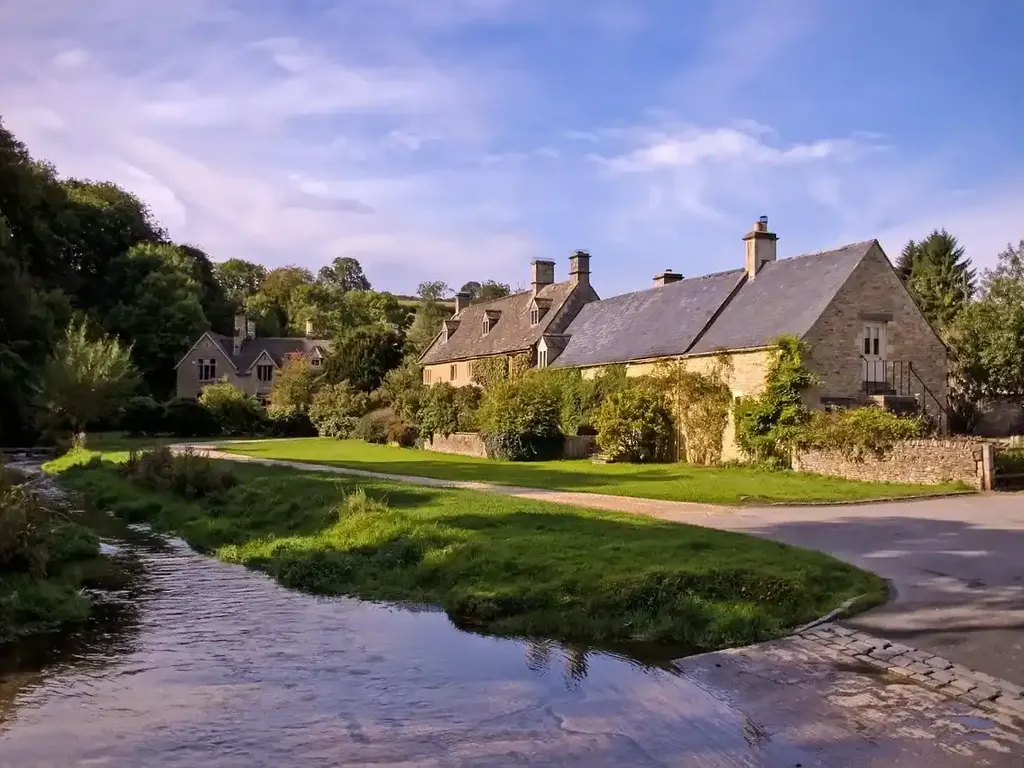 Stone cottages beside a stream in a Cotswolds village, a common swap day in a weekly hire
