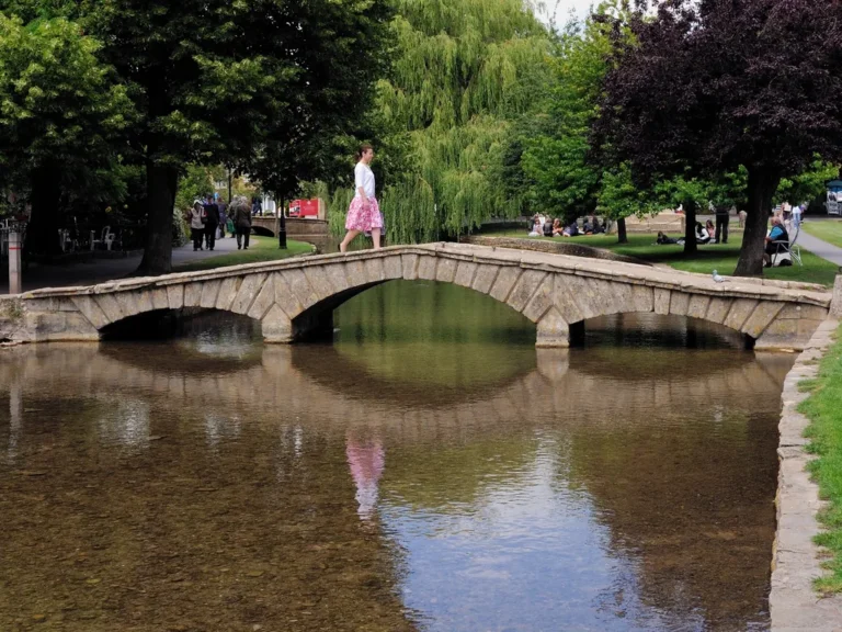 A low stone footbridge over the shallow River Windrush at Bourton-on-the-Water
