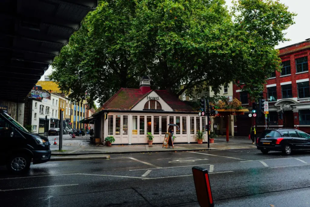 A small cafe on a rainy street corner in London under a bare autumn tree
