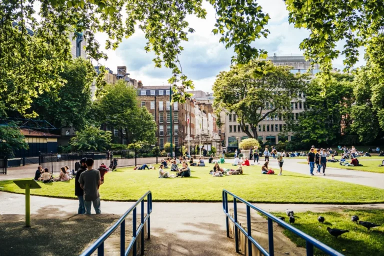 Visitors relaxing in a sunny London park, typical weather in London in August