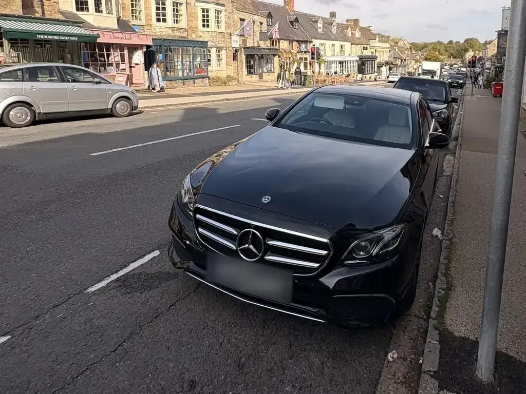 سيارة مرسيدس E-Class سوداء في الشارع الرئيسي ببلدة بورفورد في الكوتسوولدز، أكتوبر 2026