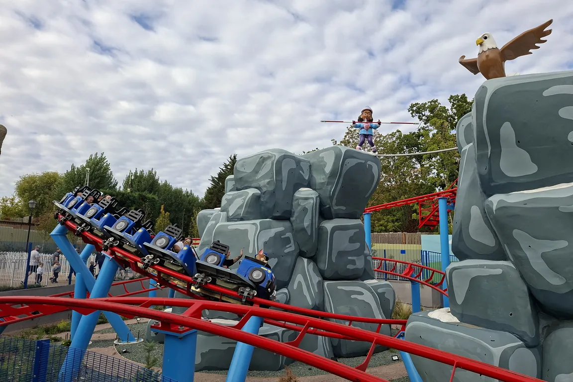 A children’s roller coaster curving between themed rock towers at Chessington World of Adventures
