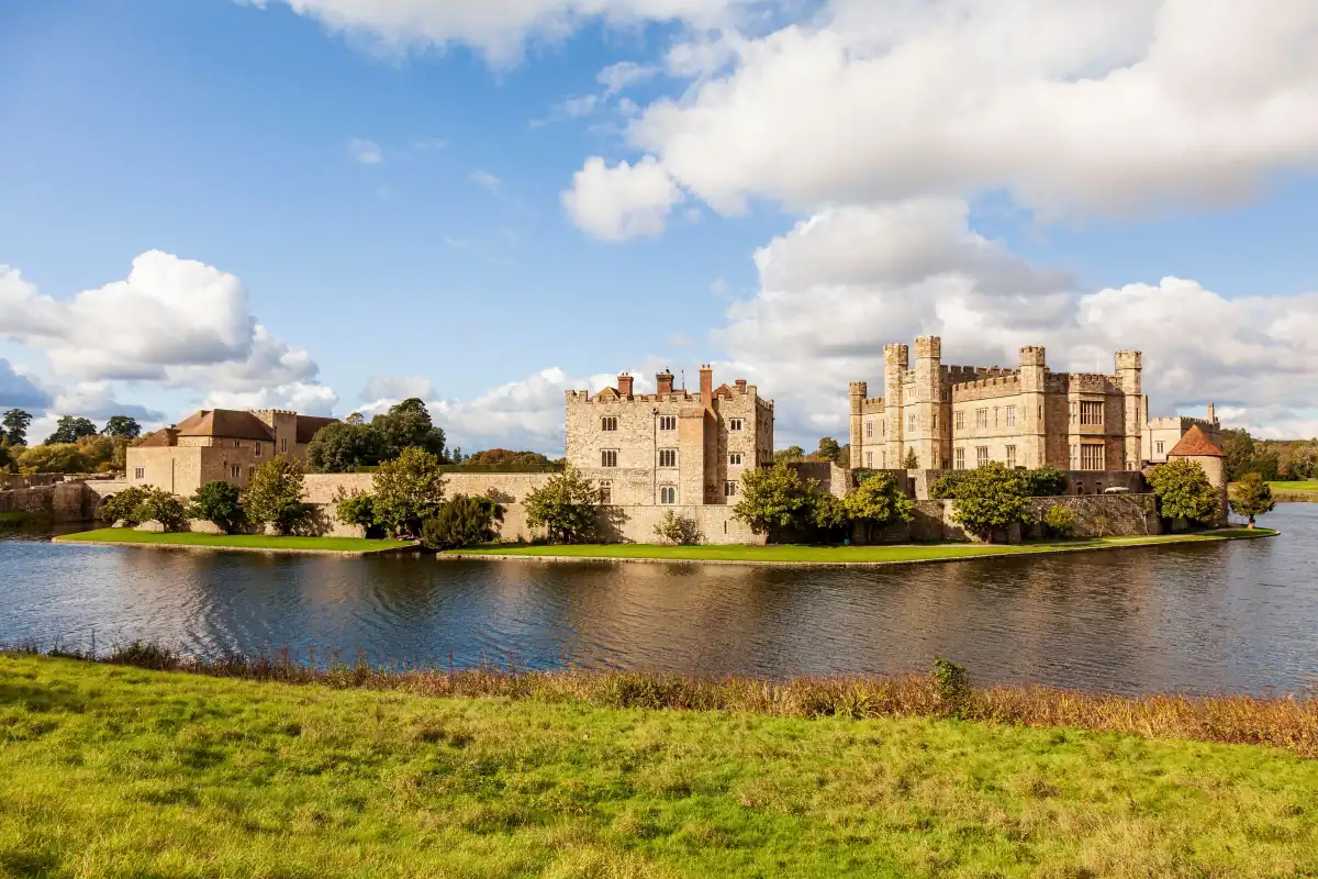 Leeds Castle in Kent seen across its moat with green lawn in front