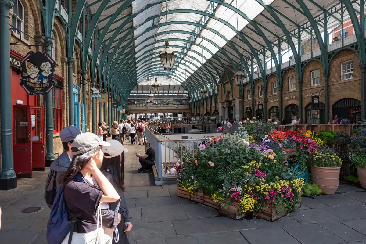 Covent Garden market hall with flower stalls, an optional afternoon stop on a London shopping tour with a driver