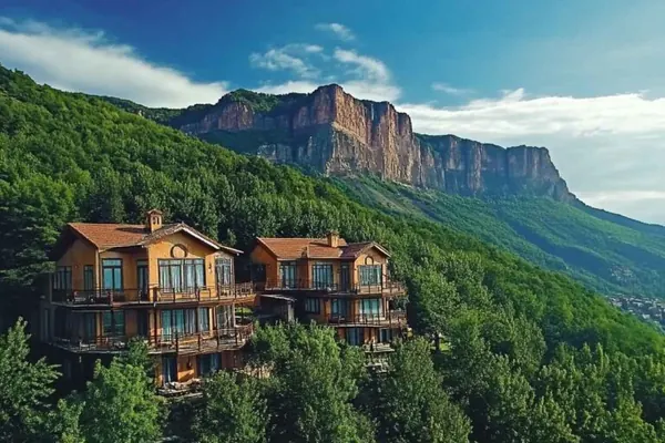 Wooden houses on a green hillside below cliffs near Trabzon