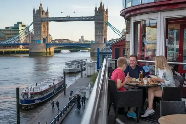 Diners on a riverside terrace with Tower Bridge beyond the Thames